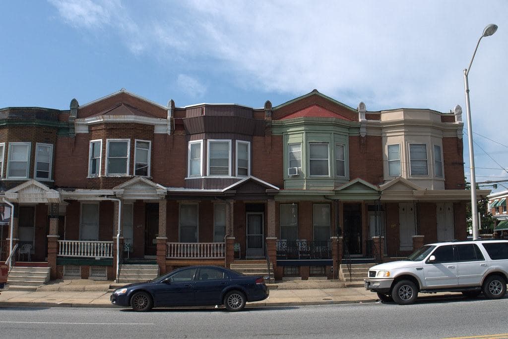 A row of brick Baltimore rowhouses with front porches along Edmondson Avenue